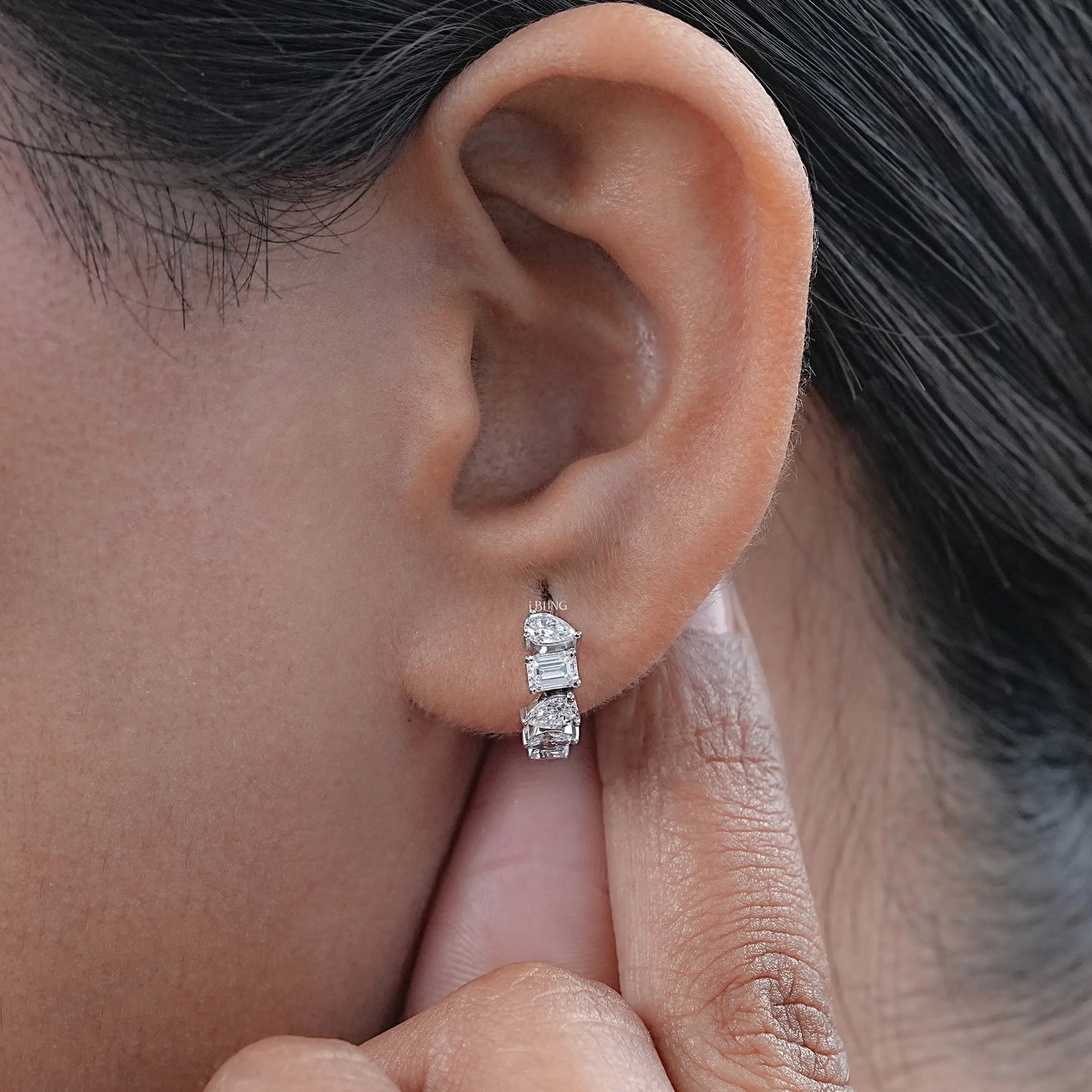 Silver huggie earrings on earlobe with classic design, perfect for sensitive ear
