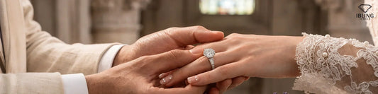 Close up view of a groom placing a round diamond white gold engagement ring with baguette side stones on a bride's finger.