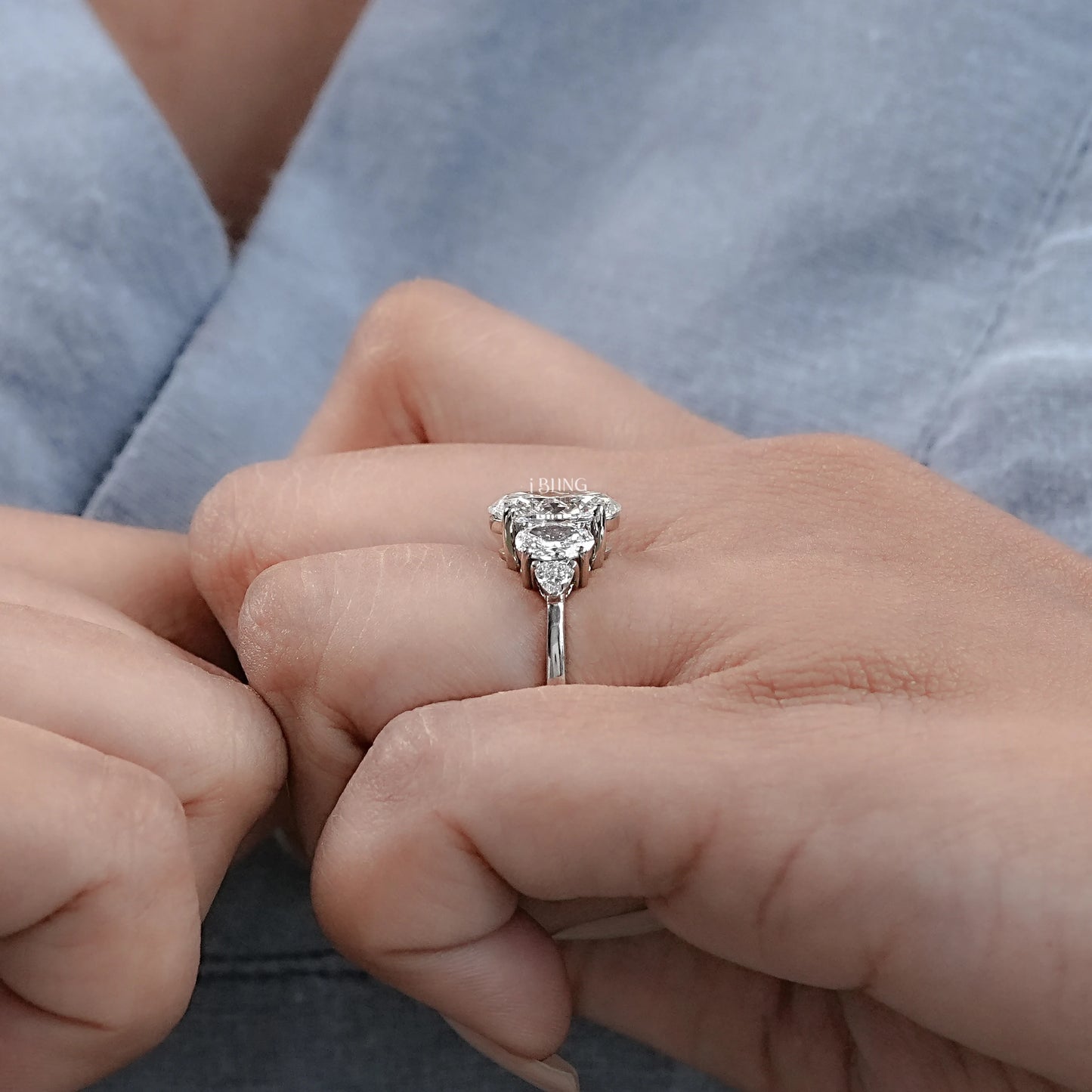 Hand holding Trillion Lab Grown Diamond Engagement Ring with Oval center and Five Stone arrangement