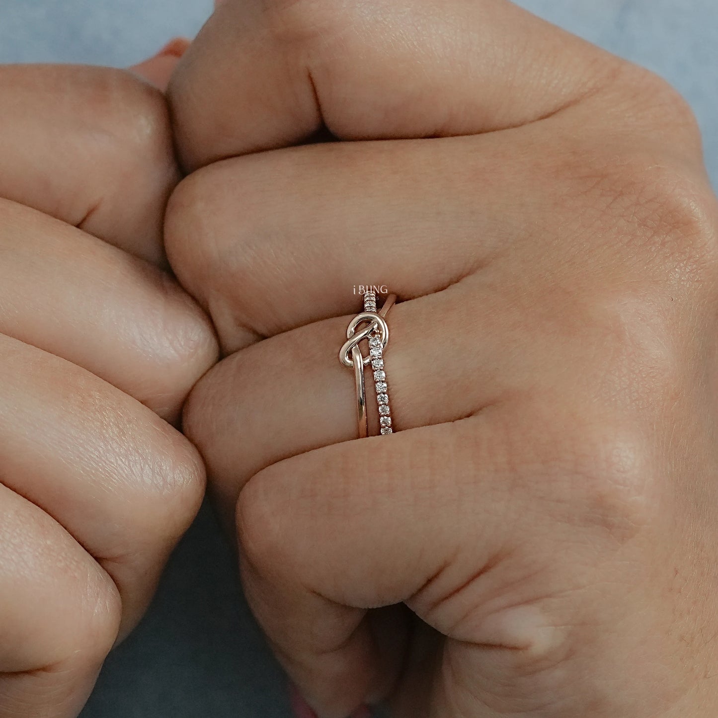 Model hand round cut wedding band featuring knot style diamond setting