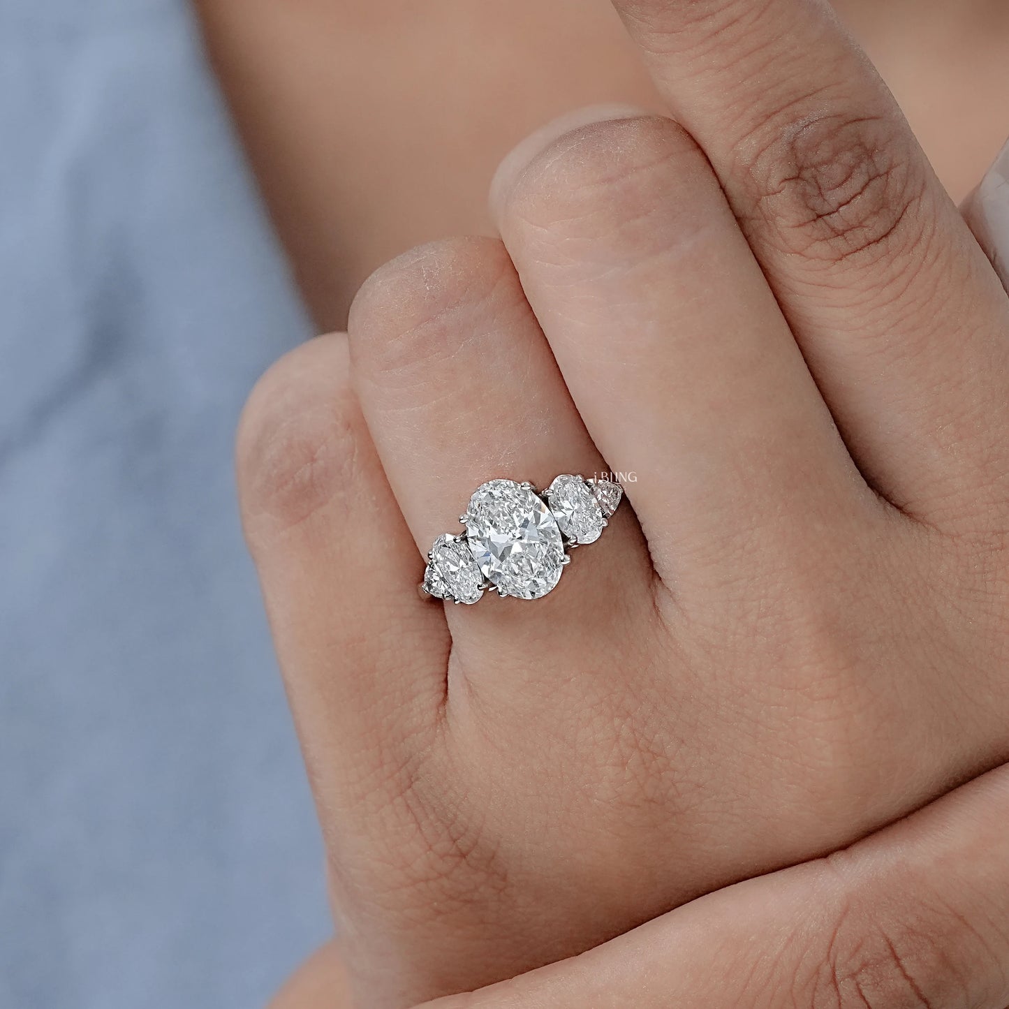 Woman hand wearing Oval Five Stone Lab Grown Diamond Engagement Ring with Trillion cut for proposal