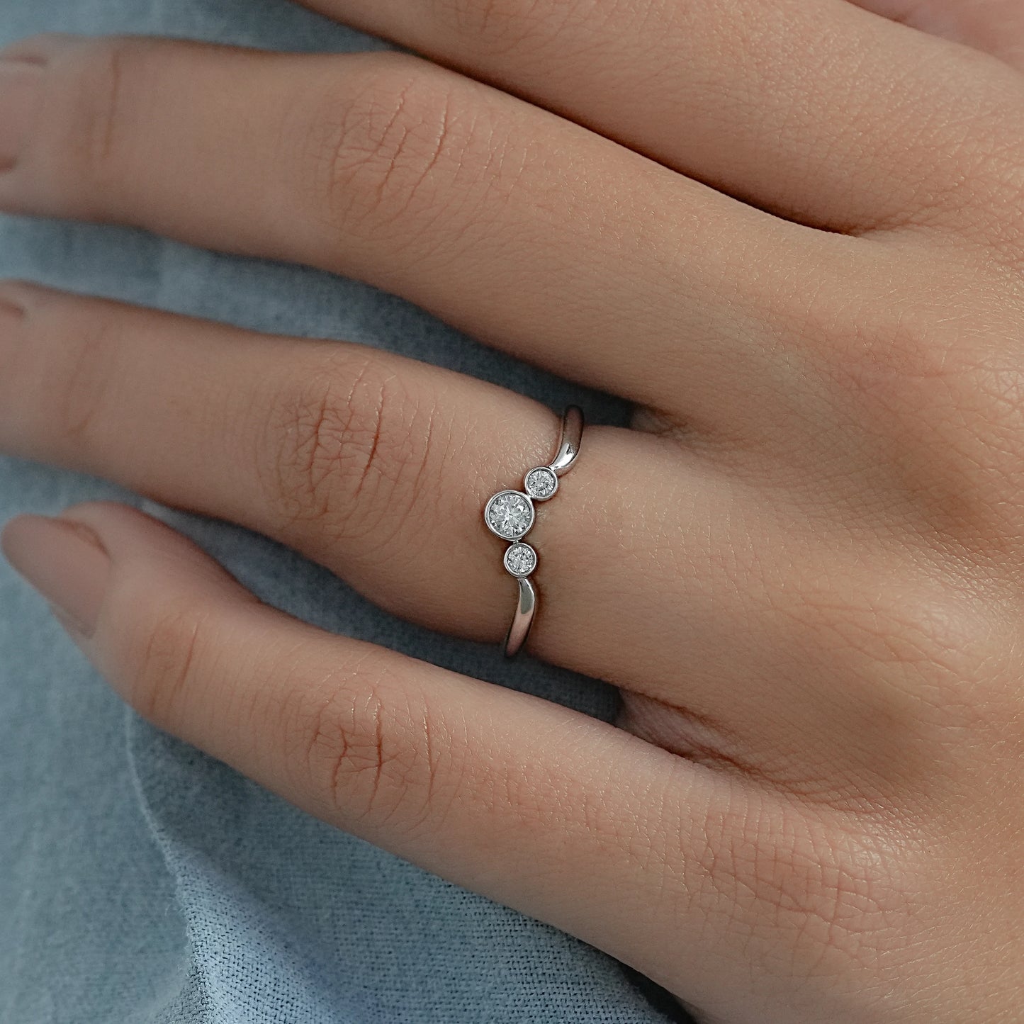 Radiant bezel set diamond wedding bands worn on a finger for a sleek and modern bridal look.