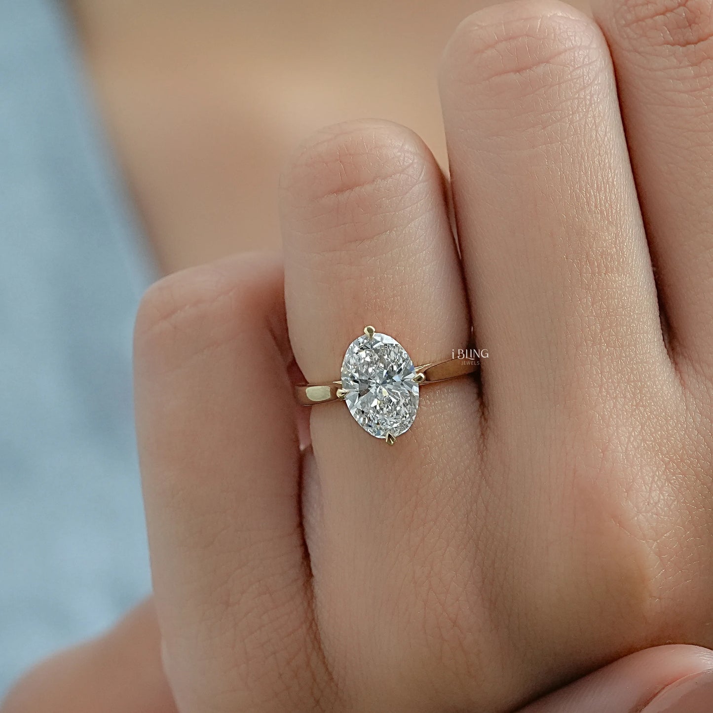 Woman hand holding an oval lab diamond engagement ring showcasing a high-definition center stone.