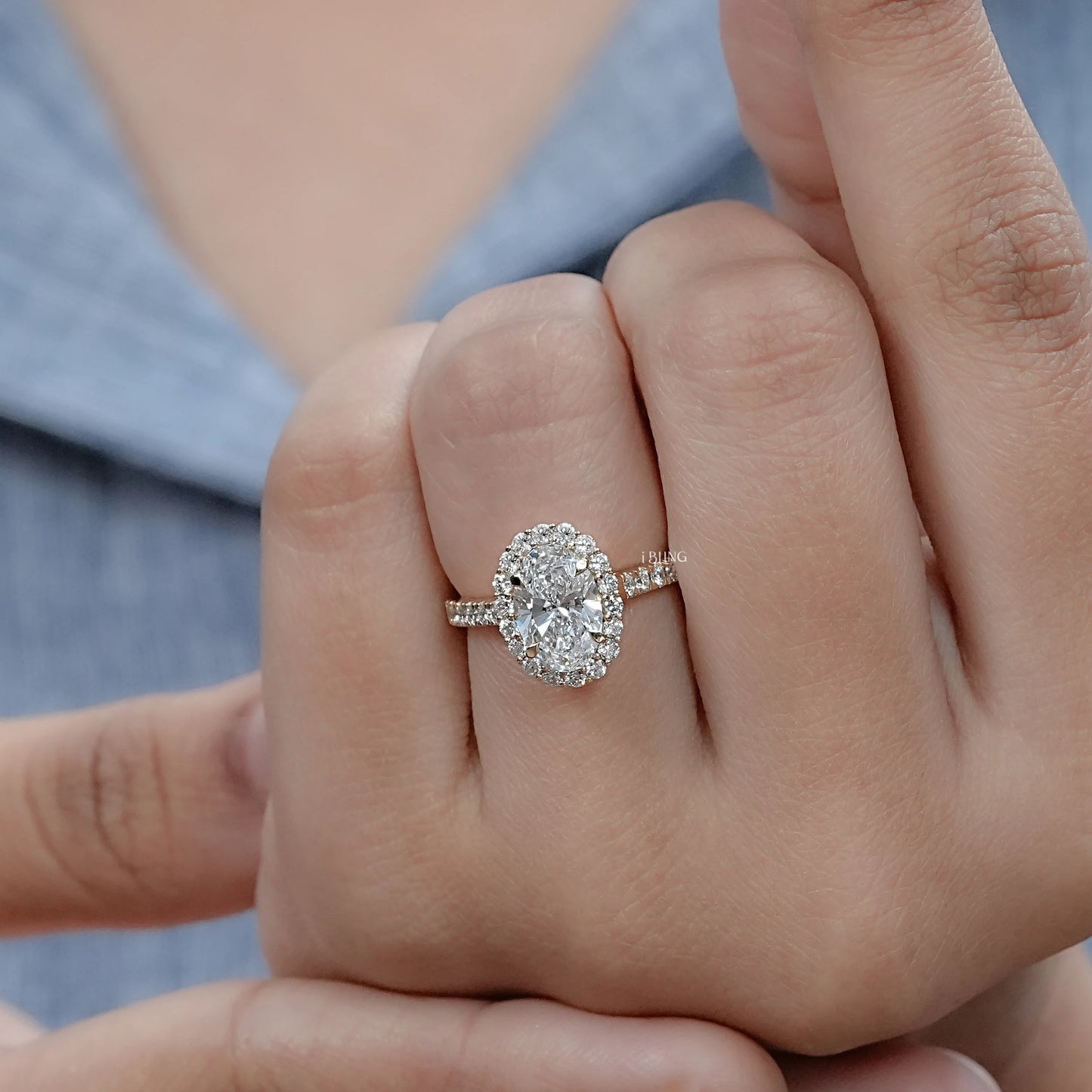 Woman hand wearing Oval halo engagement ring with lab diamond center, a chic fine jewelry choice