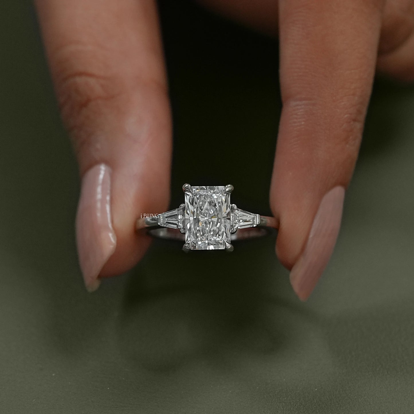 Front angle of a radiant diamond three stone design with lab grown center, ideal bridal jewelry