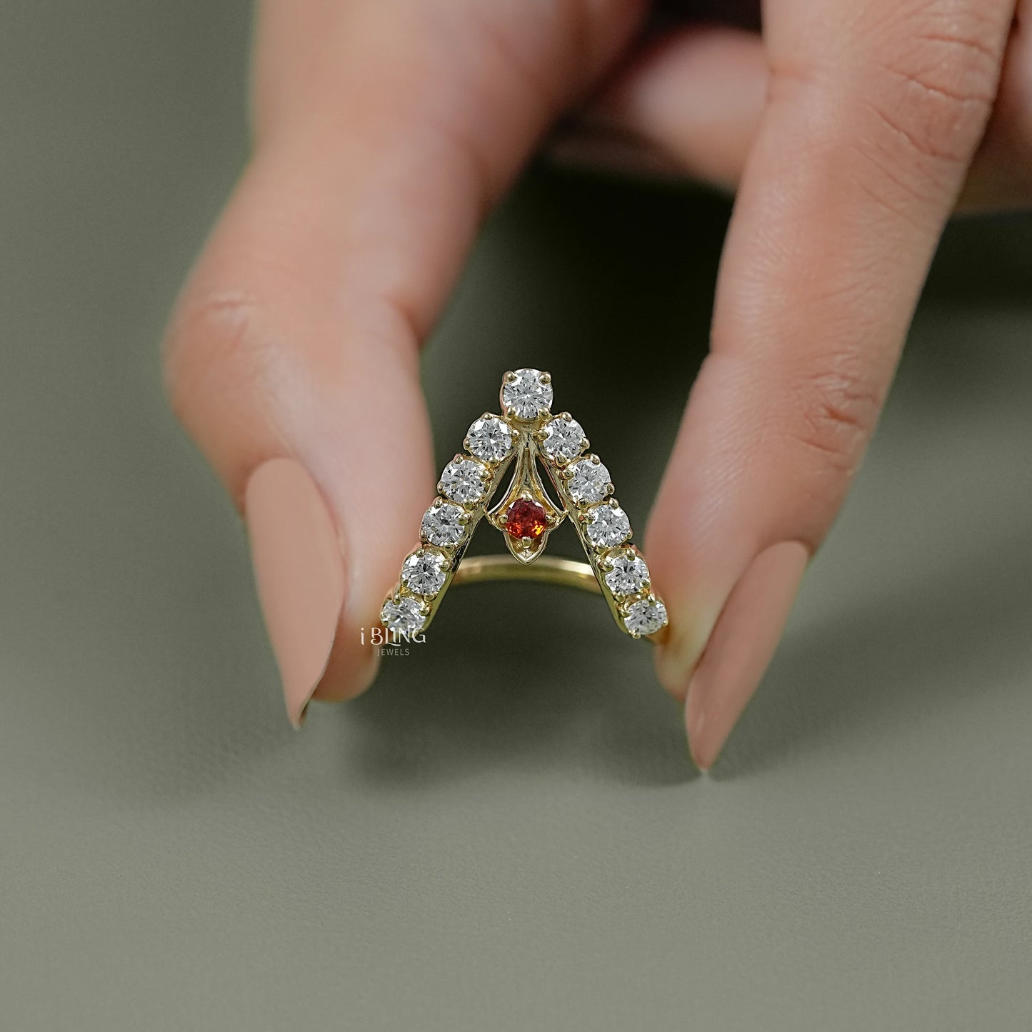 Close-up of a wishbone ring gold band encrusted with brilliant-cut diamonds and a central ruby stone.
