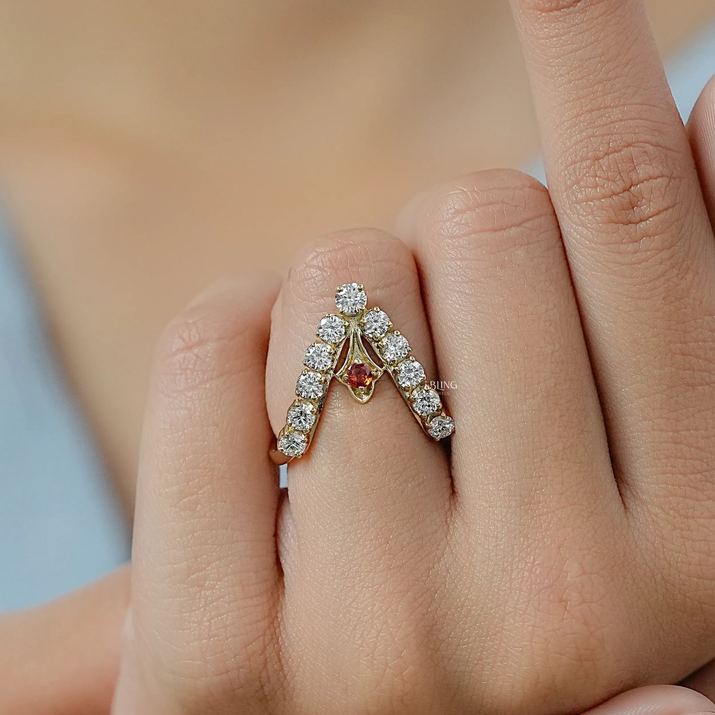 Woman hand holding a diamond and ruby engagement ring with a modern chevron wishbone style.